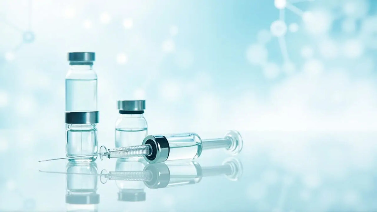 Clear glass vials with silver caps and a matching syringe on a reflective surface for injecting peptide supplements safely