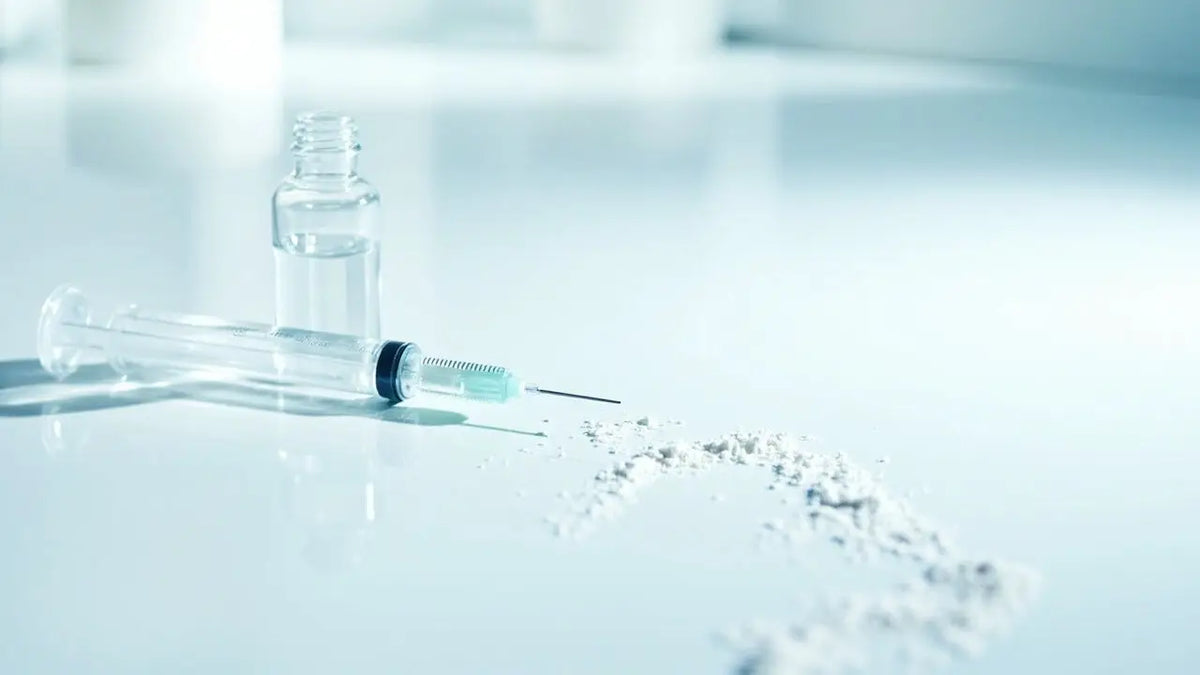 Clear glass syringe with black plunger and metallic needle beside a small vial of liquid for peptides in india guide